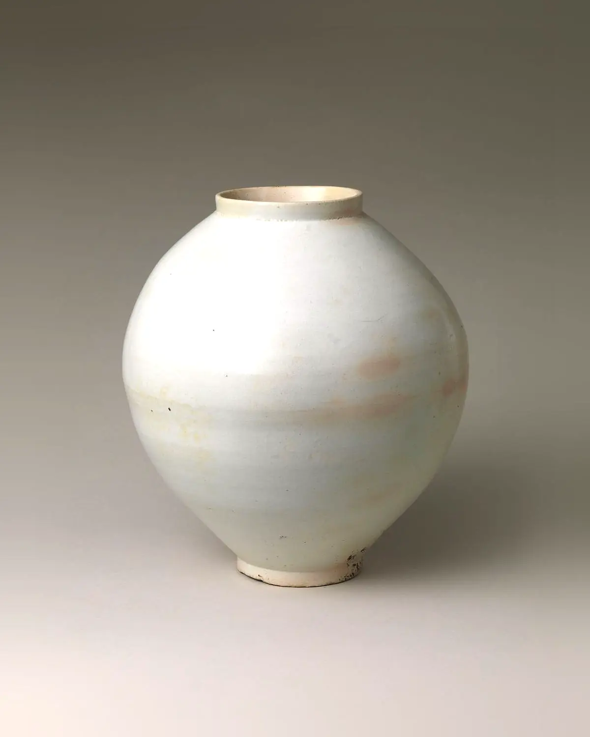 A white porcelain moon jar with a soft, slightly lopsided belly